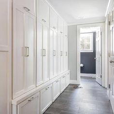 a long hallway with white cabinets and drawers on both sides, leading to an open door