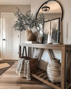 a wooden table topped with vases next to a mirror and potted plant on top of it