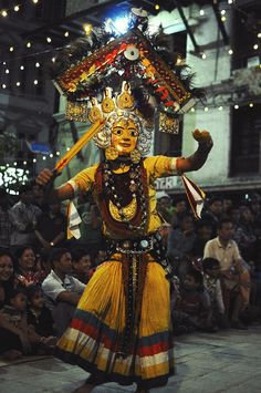 a person dressed in an elaborately designed costume and headdress, dancing with other people