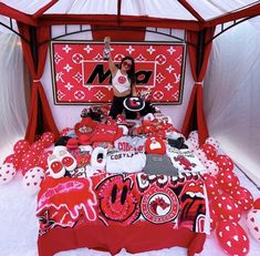 a woman standing in front of a bed covered with red and white sheets, polka dots