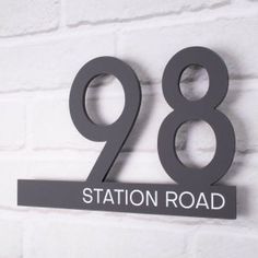 a metal sign that says station road on the side of a brick wall in front of a white brick wall