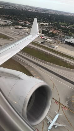 an airplane wing is seen from above the plane's engine and landing strip, with other planes in the background