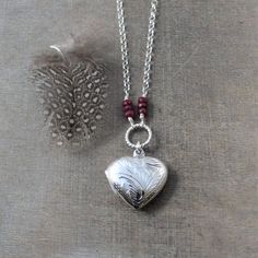 This sterling silver locket is engraved with a swirl pattern on the front and back.  The heart shaped locket opens revealing two frames awaiting your treasured photos.  The pendant is suspended from a braided ring accented with stacks of little genuine ruby rondelles (July birthstone) and set on a sterling silver rolo chain finished with a lobster clasp.The locket is also available in a round shape; this option is available at checkout.  All other birthstone also available.  Locket 20mmNecklace Sterling Silver Heart Locket Jewelry, Silver Double Heart Engraved Necklaces, Silver Jewelry With Heart Beads And Round Pendant, Silver Medallion Necklace With Heart Charm, Sterling Silver Etched Heart Jewelry, Silver Heart Charm Medallion Locket Necklace, Silver Medallion Locket Necklace With Heart Charm, Etched Heart Silver Jewelry, Silver Heart Charm Medallion Necklace