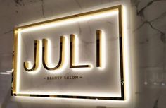 the logo or sign for a beauty salon is lit up in gold and white marble