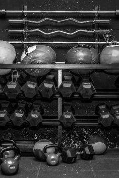 black and white photograph of kettles and dumbbells on a rack in a gym