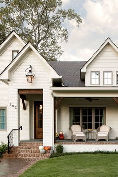 a white house with two chairs on the front porch and steps leading up to it