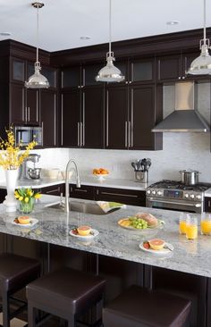 a kitchen with brown cabinets and marble counter tops, along with an appliance that reads houzz