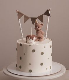 a white cake topped with a teddy bear and bunting