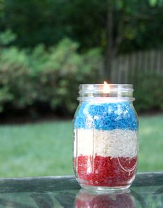 a jar filled with red, white and blue rice sitting on top of a glass table