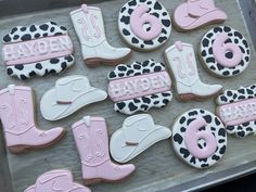 decorated cookies with cowboy boots and pink frosting are on a baking sheet, ready to be eaten