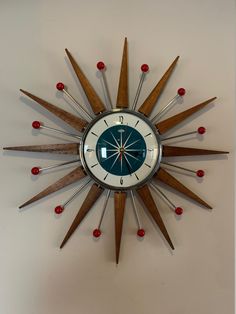 a clock that is on the wall with red balls around it and an arrow in the middle