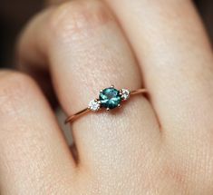 a woman's hand with a ring on it that has a blue stone in the middle