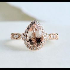 an engagement ring with a pear shaped morganite surrounded by white and brown diamond accents