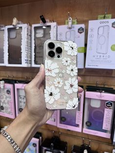 a woman holding up her phone case in front of the camera at a store display