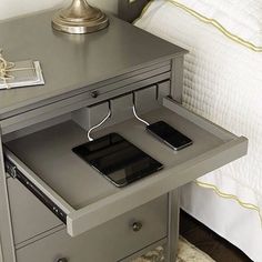 a bedside table with two cell phones on it