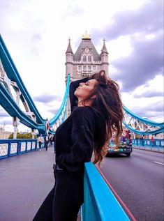 a woman leaning on the edge of a bridge