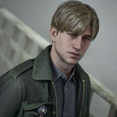 a man in a green jacket standing next to a stair case and looking at the camera