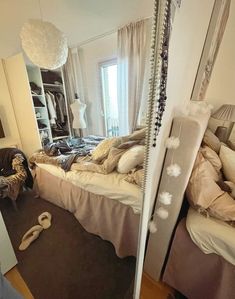 a bedroom with a bed, mirror and clothes on the floor in front of it