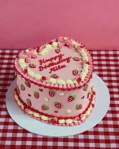 a heart shaped cake on a table with red and white checkered tablecloths