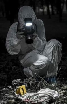 a person in a white suit is holding a camera and kneeling down on the ground