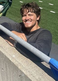 a man sitting on the side of a cement wall next to a blue and white frisbee