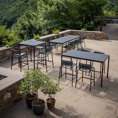 an outdoor dining area with tables and chairs, surrounded by greenery on the hillside