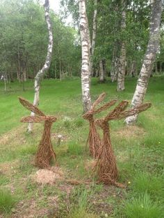 two sculptures made out of sticks in the grass