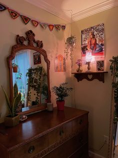 a dresser and mirror in a room with plants on the wall, potted plant next to it