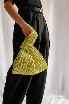 a woman is holding a yellow purse in her hand