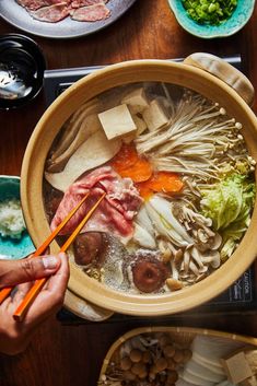 a person holding chopsticks above a bowl of food