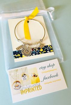 a yellow ribbon is attached to a bracelet with charms and an embellishment card