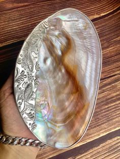 a person holding a silver plate with an animal in it's center on a wooden table