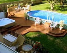 an above ground pool surrounded by wooden decking and patio furniture with chairs around it