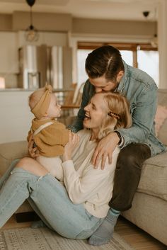 a man and woman are sitting on the floor with a baby in their lap,