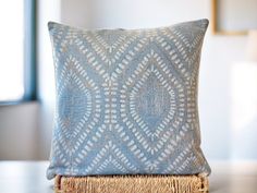 a blue and white pillow sitting on top of a wooden table