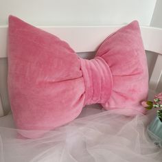 a pink bow tie sitting on top of a white chair next to a vase with flowers