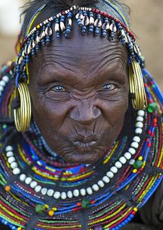 an african woman with large hoop earrings and beaded headdress, looking at the camera