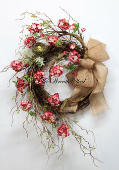 a wreath with pink flowers and greenery tied to it on a white background,