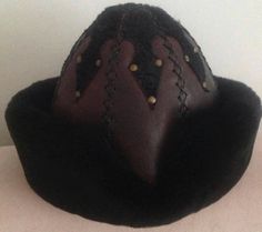 "Completely hand stitched Handmade This Leather hat is extremely thick and very warm.Made Genuine leather and Sheep Fur. Please be sure to measure the size of your head before buying. Measuring; Measuring for your head size is, You can use a tape measure (or a length of string that you will have to hold up to a tape measure) to determine the length. Place the string or tape around your head about 1/8\" above your ear, across the mid-forehead, completely circling your head. Hold the tape firmly, Handmade Artisan Black Hats, Brown Handmade Mini Hats With Curved Brim, Handmade Brown Mini Hat With Short Brim, Handmade Brown Mini Hats With Curved Brim, Traditional Handmade Black Hat Bands, Handmade Brown Brimmed Costume Hats And Headpieces, Handmade Western Brimmed Costume Hats And Headpieces, Handmade Western Brimmed Costume Hat, Traditional Handmade Costume Hats And Headpieces