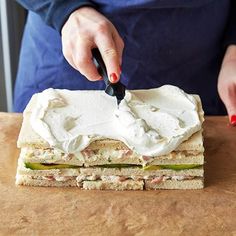 a person cutting up a sandwich on top of a wooden table