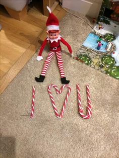 an elf laying on the floor next to some candy canes and a love sign