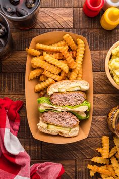 a hamburger and french fries are sitting on a wooden table next to some condiments