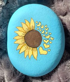 a blue and yellow painted rock with a sunflower on it