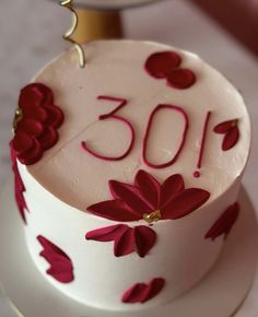 a white cake with red flowers and the number 30 on it's top is sitting on a table