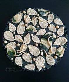 a cake decorated with leaves and berries on top of a black plate, ready to be eaten