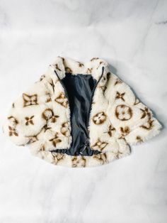 a white and brown jacket with skulls on it sitting on top of a marble surface