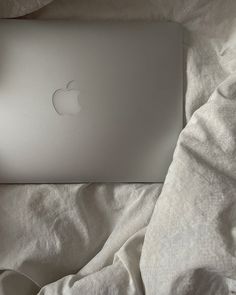 an apple laptop sitting on top of a bed