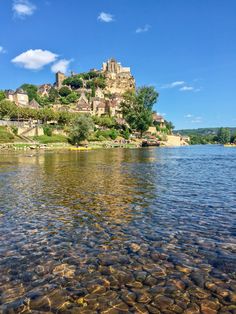 an old castle sits on top of a hill above the water