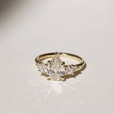 a yellow gold ring with three pear shaped diamonds