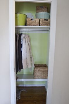 an open closet with clothes and baskets on the shelves